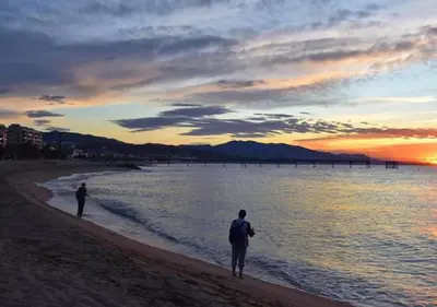 two people walking on the beach at sunset at CasaBala - Near the beach and Barcelona center in Badalona