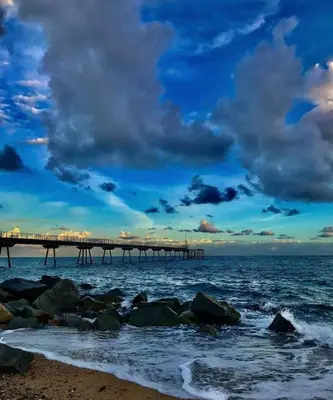 a pier on the beach with rocks in the water at CasaBala - Near the beach and Barcelona center in Badalona