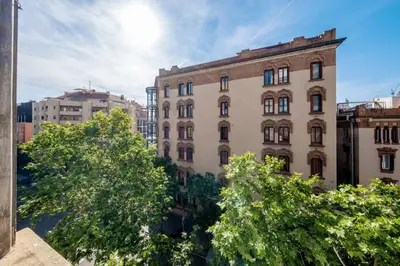 a building in a city with trees in the foreground at BeBarceloner Eixample Apartments - 4 bedrooms in Barcelona