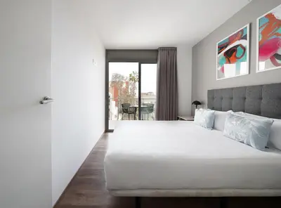 a bedroom with a large white bed and a balcony at Numa Barcelona Colmena in Barcelona