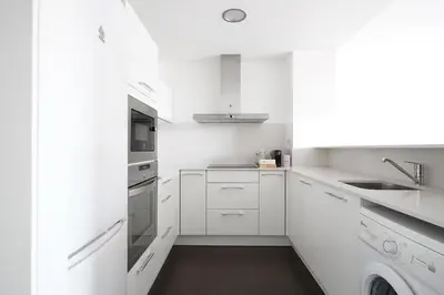 a white kitchen with white cabinets and a sink at Numa Barcelona Colmena in Barcelona