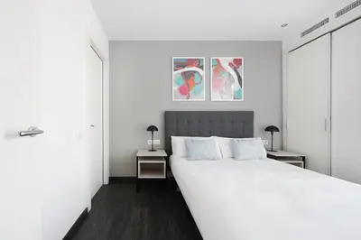 a white bedroom with a large bed and two tables at Numa Barcelona Colmena in Barcelona