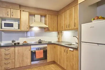 a kitchen with wooden cabinets and a white refrigerator at BeBarceloner Sant Andreu Apartments - 1 bedroom in Barcelona