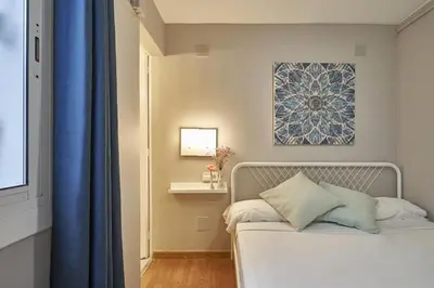 a bedroom with a white bed with a blue curtain at BeBarceloner Sant Andreu Apartments - 1 bedroom in Barcelona