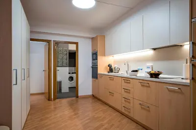 a kitchen with white cabinets and wooden floors at Habitat Apartments Ribes in Barcelona