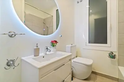 a white bathroom with a sink and a mirror at SAGRADA FAMILIA C&D Lovely Apartment in Barcelona