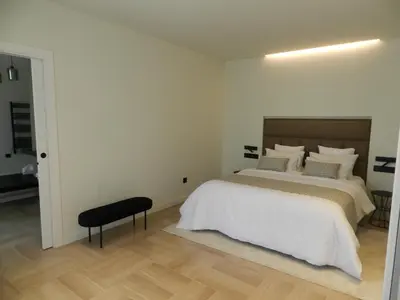 a white bedroom with a bed and a black stool at HOTEL MANEL in Martorell