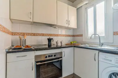 a kitchen with white cabinets and a sink and a dishwasher at AB Nou de la Rambla in Barcelona