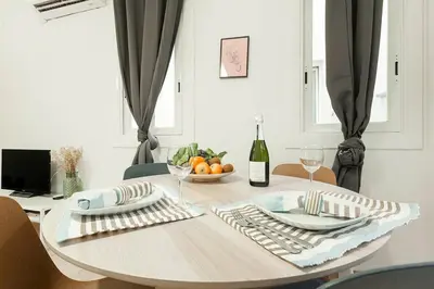 a dining room table with a bowl of fruit and a bottle of wine at The Collection Barcelona - Comfortable 3BD in Poblenou next to the beach only for Families! in Barcelona