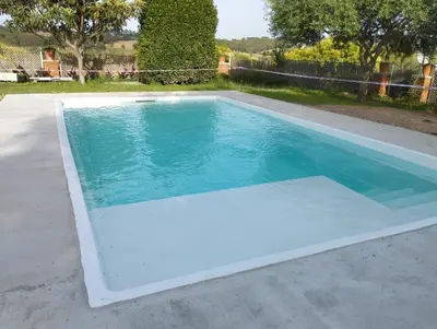 a swimming pool with blue water in a backyard at Winahost Casa familiar con piscina in Santa Eulalia de Ronsaná
