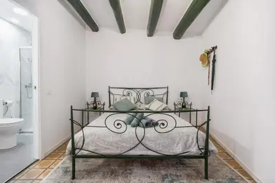 a bedroom with a wrought iron bed and a bathroom at La Casa Vella EL BEDORC in Piera