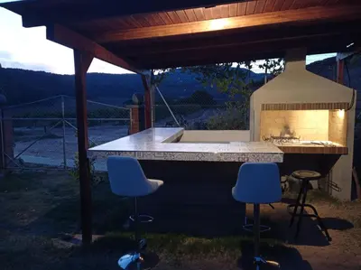 a outdoor kitchen with two blue chairs under a pergola at La Casa Vella EL BEDORC in Piera