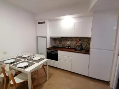 a kitchen with white cabinets and a table and chairs at Piso pl 2A, 20 min Plaza Cataluña in Sant Adria de Besos