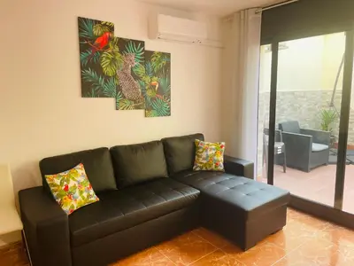 a living room with a black leather couch and paintings on the wall at Beach Apartment Artigas in Badalona