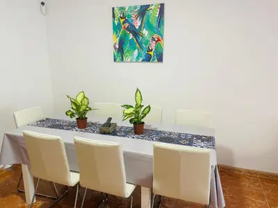 a dining room table with white chairs and a painting at Beach Apartment Artigas in Badalona
