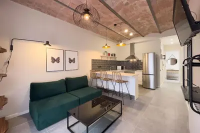 a living room with a green couch and a kitchen at BeBarceloner Sants Apartments - 2 bedrooms in Barcelona
