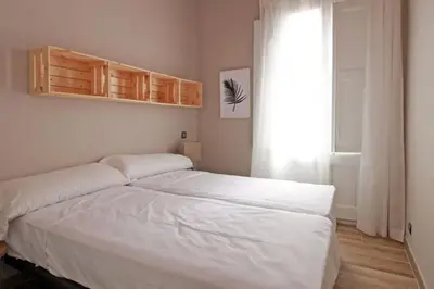 a white bed in a room with a window at BeBarceloner Sants Apartments - 2 bedrooms in Barcelona