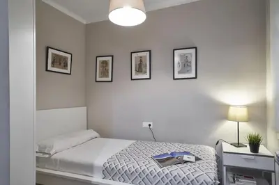 a white bedroom with a bed and three pictures on the wall at BeBarceloner Sant Andreu Apartments - 3 bedrooms in Barcelona