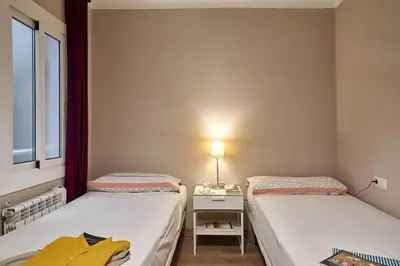 a room with two beds and a desk with a lamp at BeBarceloner Sant Andreu Apartments - 3 bedrooms in Barcelona