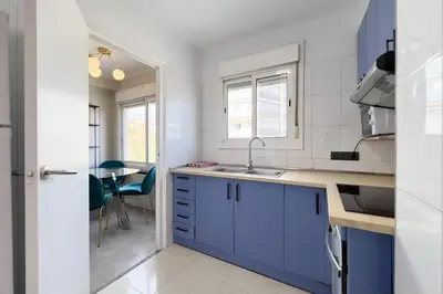 a white kitchen with blue cabinets and a table at BeBarceloner Sant Andreu Apartments - 3 bedrooms in Barcelona