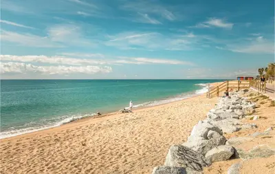 a beach with people on the sand and the ocean at Nice Apartment In Pineda De Mar in Pineda de Mar