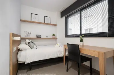 a bedroom with a bed and a desk and a window at Flateli Navas D02 in Barcelona
