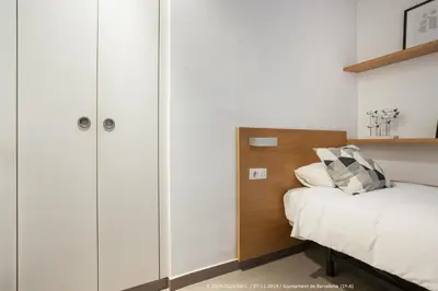 a bedroom with white walls and a bed and cabinets at Flateli Navas A01 in Barcelona