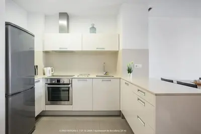a kitchen with white cabinets and a stainless steel refrigerator at Flateli Navas A01 in Barcelona