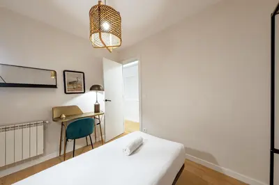a bedroom with a white bed and a desk at BeBarceloner Eixample Apartments in Barcelona