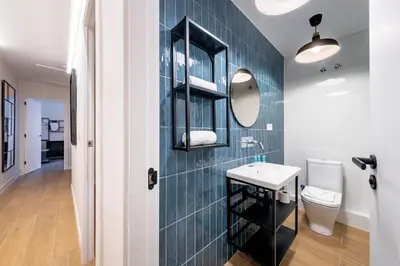 a bathroom with a blue tiled wall with a sink and a toilet at BeBarceloner Eixample Apartments in Barcelona