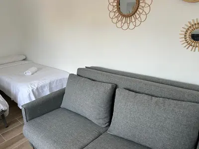 a couch and a chair in a room with a mirror at Vilamarlux VII in Vilassar de Mar