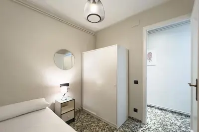 a white bedroom with a bed and a mirror at BeBarceloner Eixample Apartments - 3 bedrooms in Barcelona