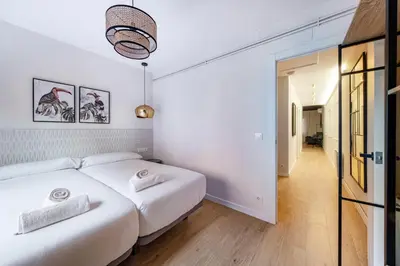 a white bedroom with two beds and a mirror at BeBarceloner Eixample Apartments - 4 bedrooms in Barcelona