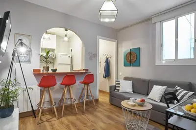 a living room with a couch and red bar stools at BeBarceloner Eixample Apartments - 2 bedrooms in Barcelona