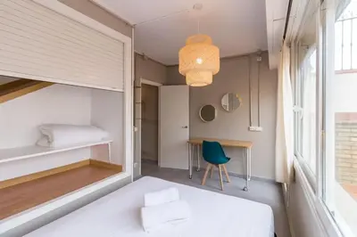 a room with a bed and a desk and a window at BeBarceloner Sant Andreu Apartments - Attic with terrace in Barcelona