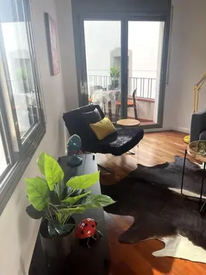 a living room with a chair and a table with a plant at Pure Bliss Apartment Sitges in Sitges