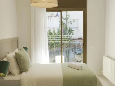 a white bedroom with a bed and a window at Sitges Spaces Bonaire Beach Condo in Sitges