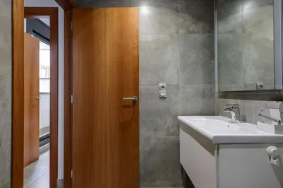 a bathroom with a sink and a wooden door at Urban Flats Vallirana in Barcelona