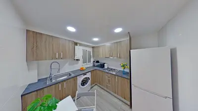 a kitchen with wooden cabinets and a white refrigerator at PREMIUM HABITAT LA RIERA in Pineda de Mar
