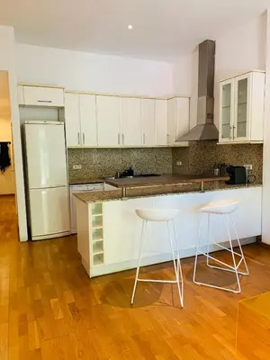 a kitchen with white cabinets and two stools at Hermoso piso en el centro de Barcelona in Barcelona