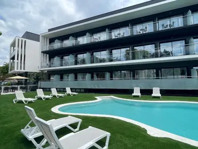 a building with a swimming pool and lounge chairs at Hotel C31 in Castelldefels