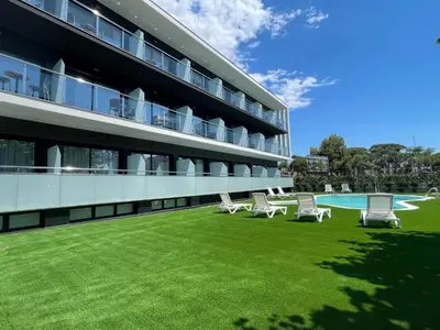 a building with a yard with chairs and a swimming pool at Hotel C31 in Castelldefels