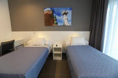 a bedroom with two beds and a tv and a window at Hotel C31 in Castelldefels