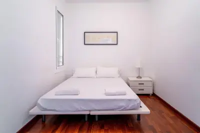a room with two white beds and a door at The Collection Barcelona - Eixample - Bright and modern 4BD only for Families or Business groups in Barcelona