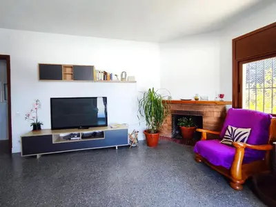 a living room with a tv and a purple chair at Casa con piscina privada en Sant Pol de Mar in San Pol de Mar