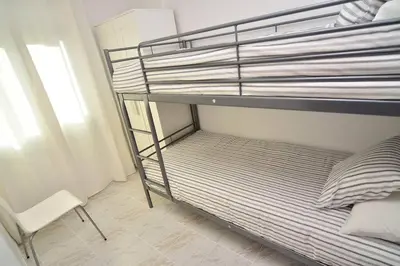 a bunk bed with a chair in a room at New! Fantastic apartament in front of the sea! in Pineda de Mar