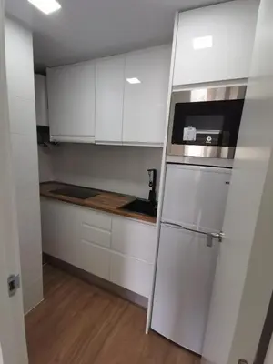 a kitchen with white cabinets and a refrigerator at Ático en Calella a 7 minutos de la playa in Calella