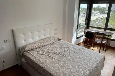 a bedroom with a bed and a desk and a window at Apartment with sea views next to the beach of Mar Bella in Barcelona